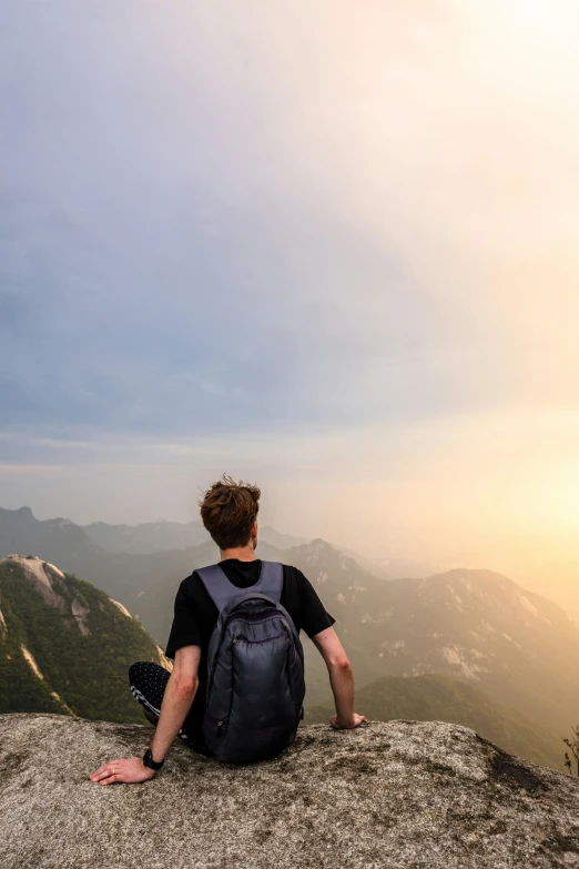 a man sitting on top of a mountain overlooking a valley