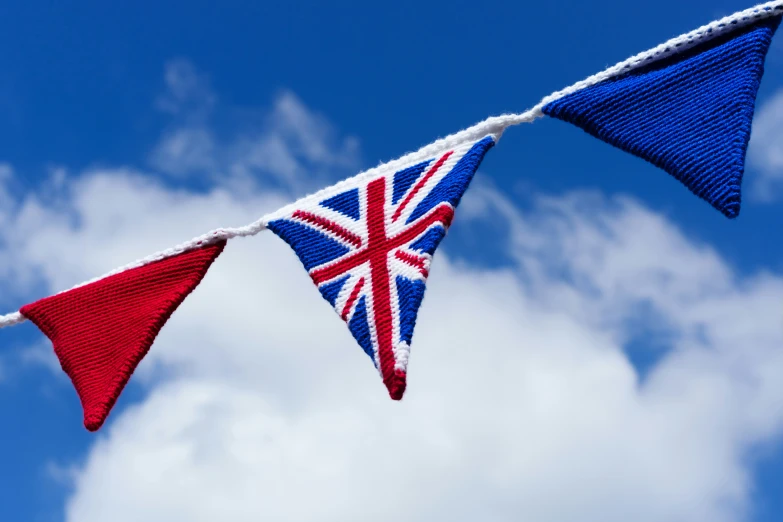 a row of knitted british and irish flags under a blue sky