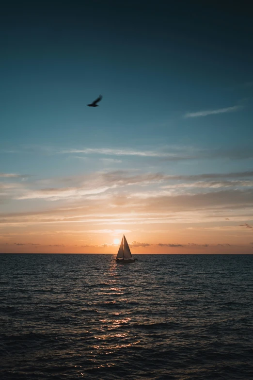 a sailboat on the water in front of a sky with clouds