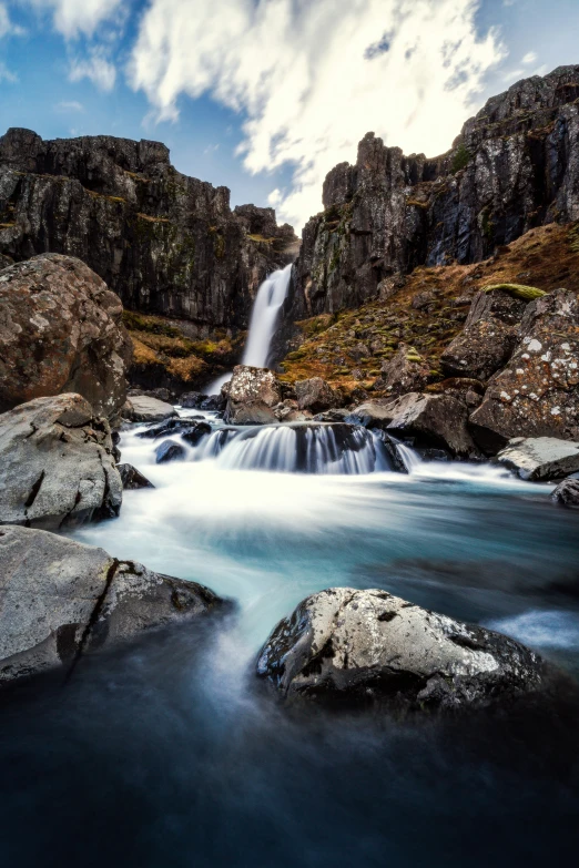 a small waterfall running into a valley with rocky hillsides