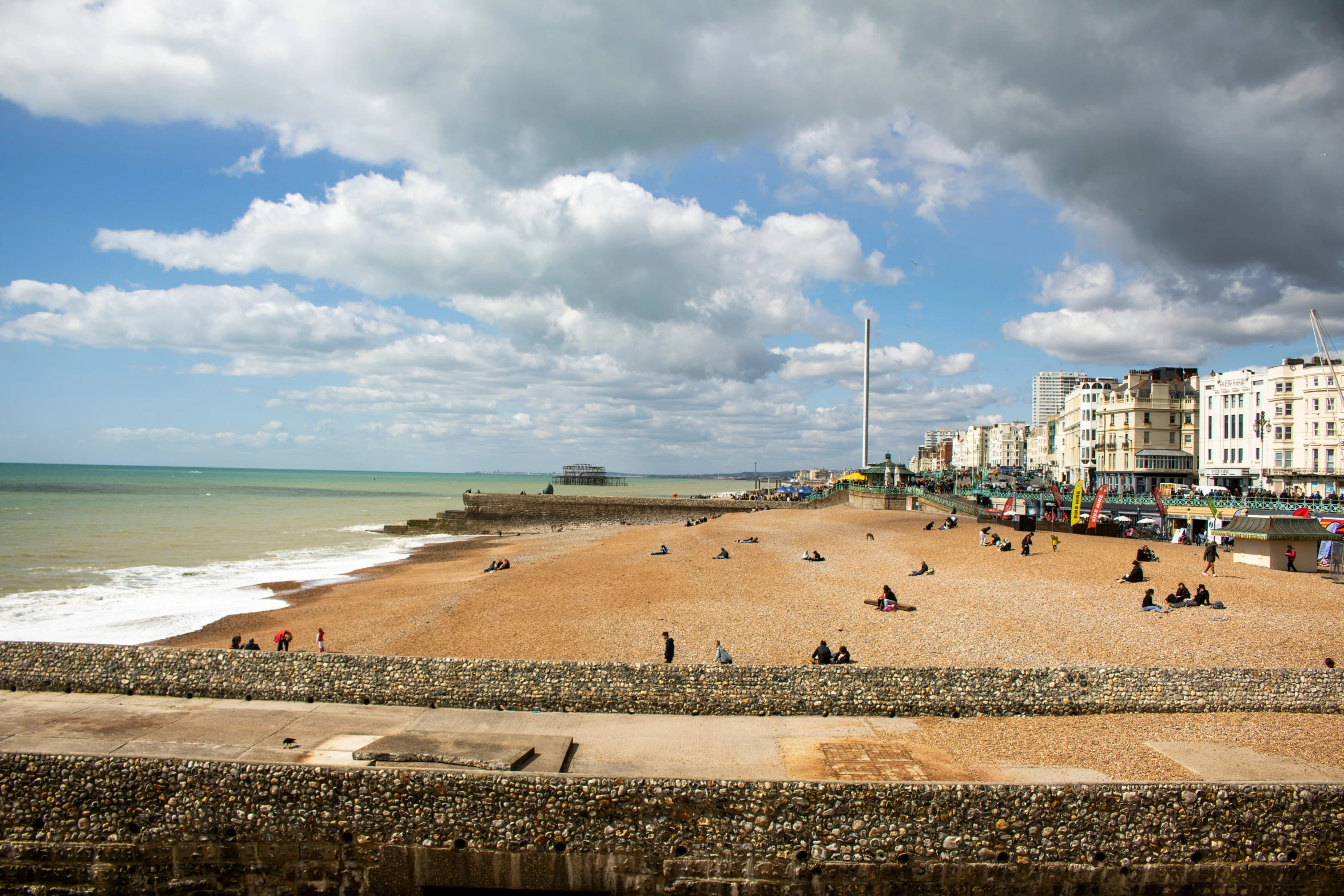 people walking along a beach next to a city