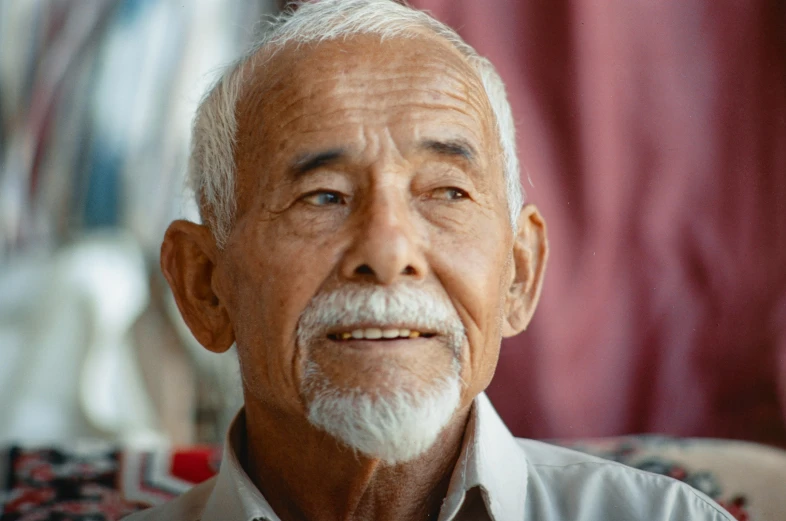 a man in a light gray shirt with white beard