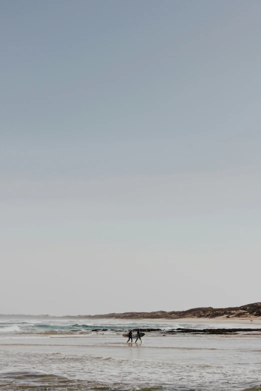 two surfers are on the shore and one has his surfboard