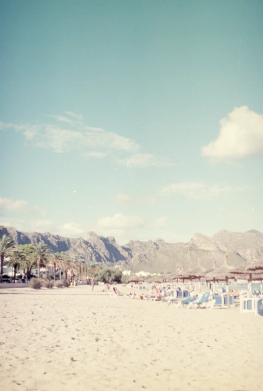 this is a pograph of a beach with mountains and beach chairs in the background