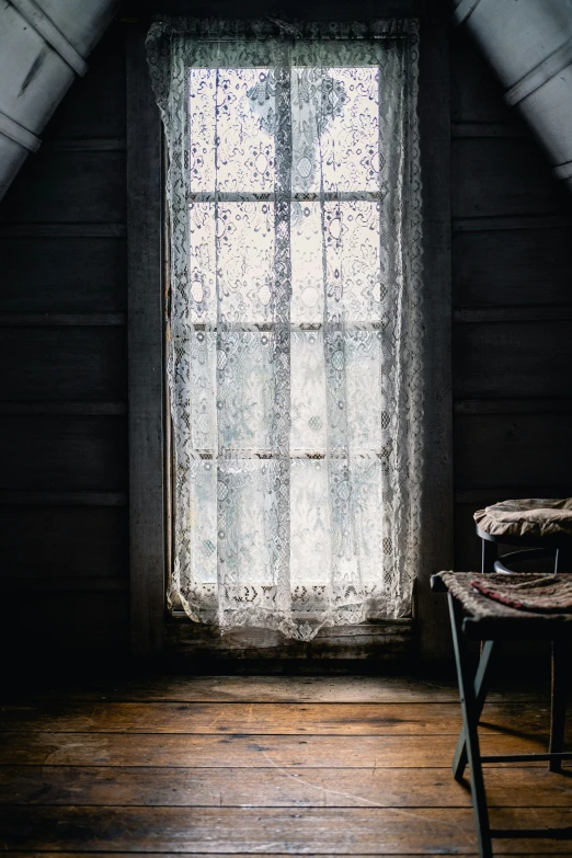 a dark room with a window next to a chair