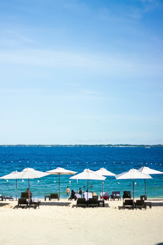 many lounge chairs and umbrellas set up on the beach