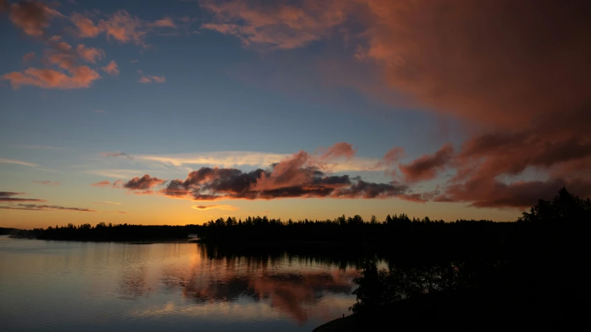 this is a calm river with trees at sunset