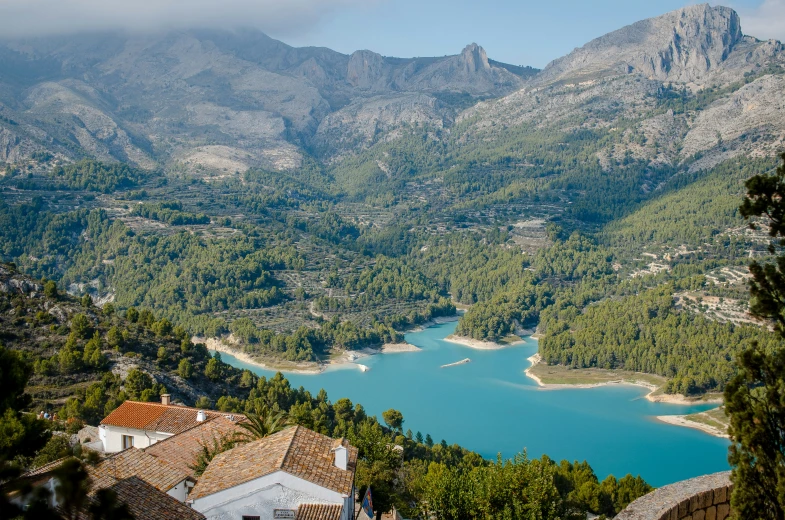 the view of the mountains, river, houses and trees from a hill