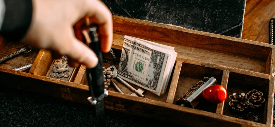 a person is putting money in an old wooden box