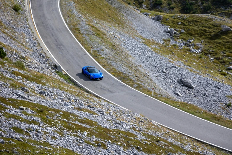 a car going down the hill on a narrow road