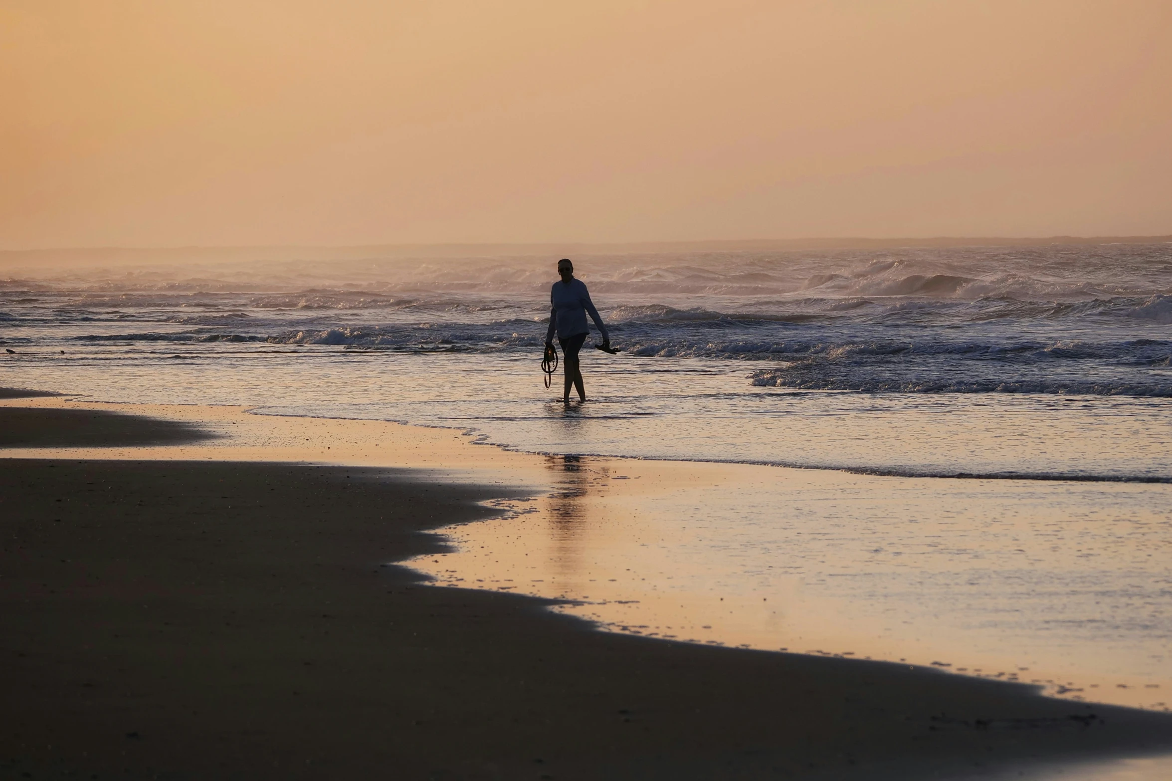 the person is walking along the beach on the waves