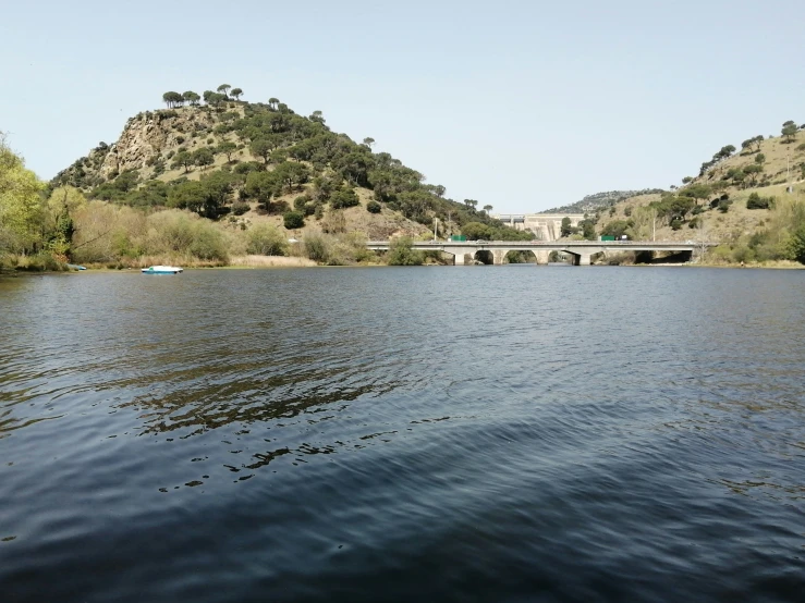 the water is calm and blue with a bridge crossing over it