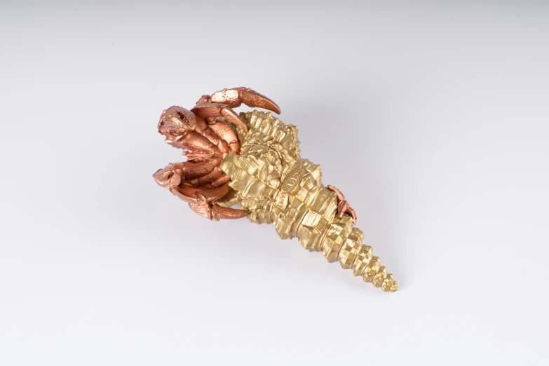 a gold - colored brooch with several beads sits against a white background