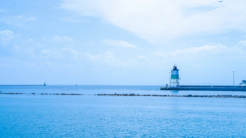 the light house is on the end of a pier