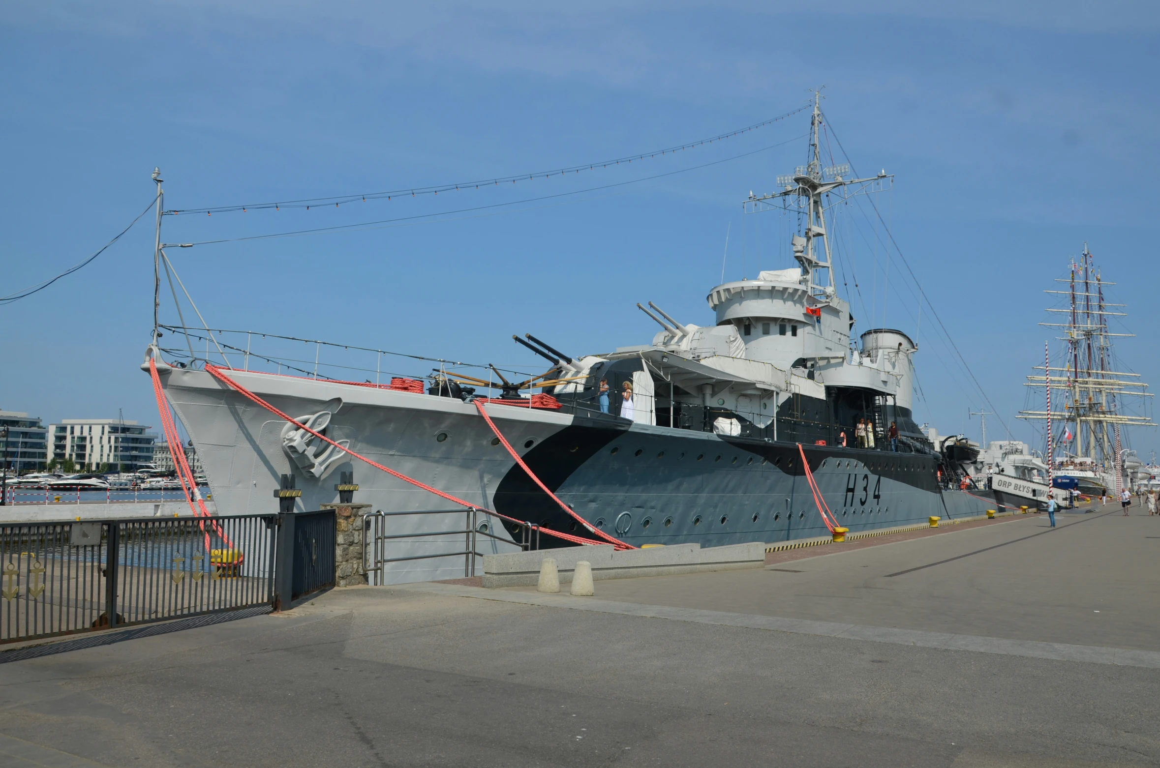 a naval ship with a tug boat at the dock