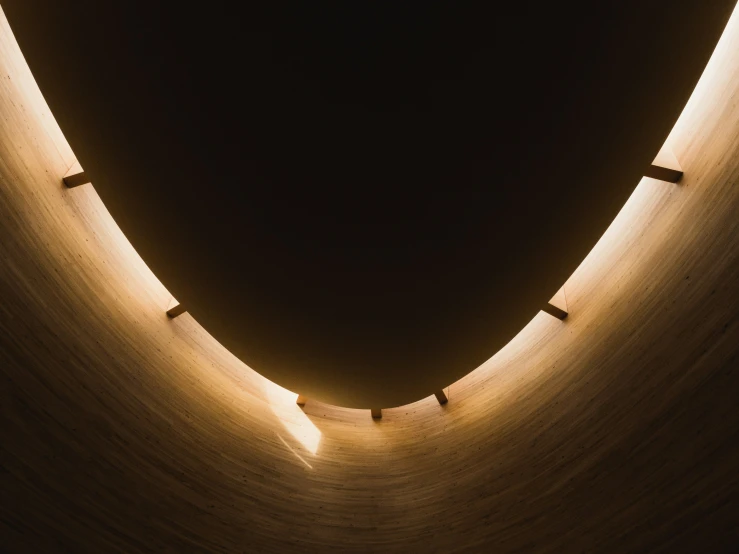 a curved, wooden wall with lights shining from its center