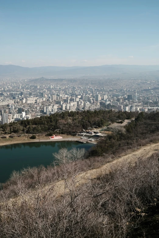 a large lake on the edge of a hill in front of city