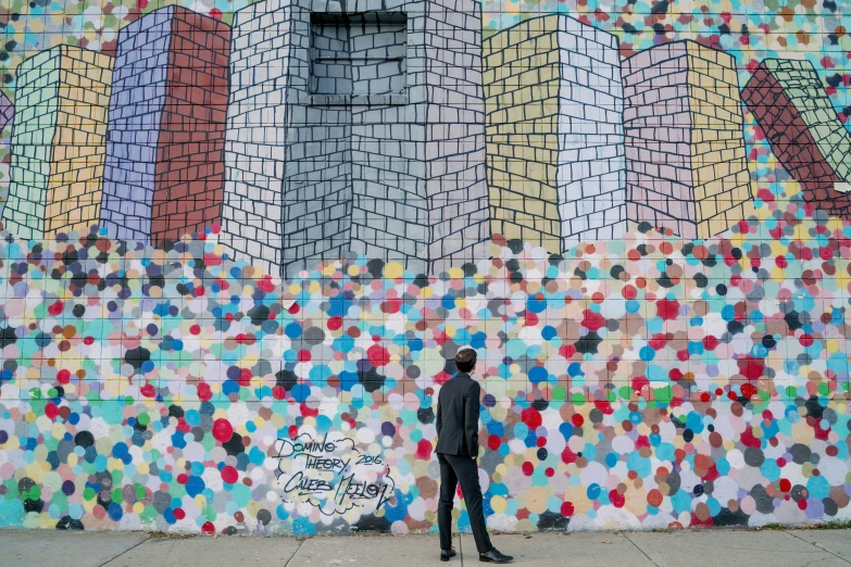 a man standing by some colorful graffiti on the side of a building