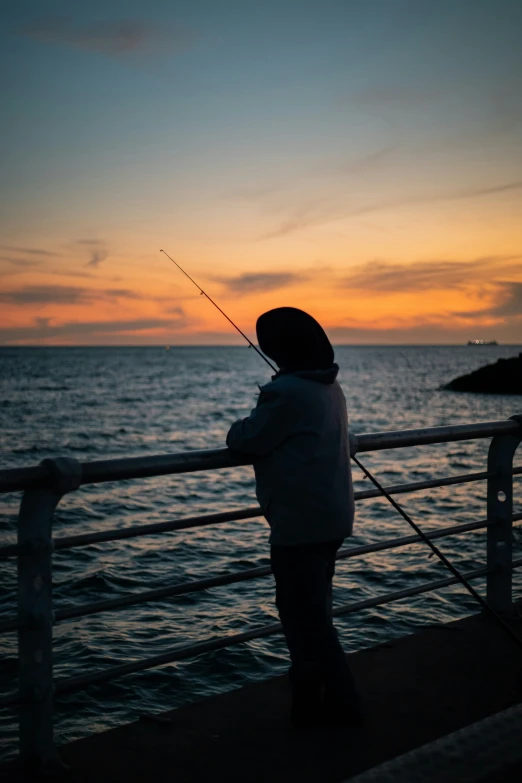 a boy is standing on the railing with his fishing rod