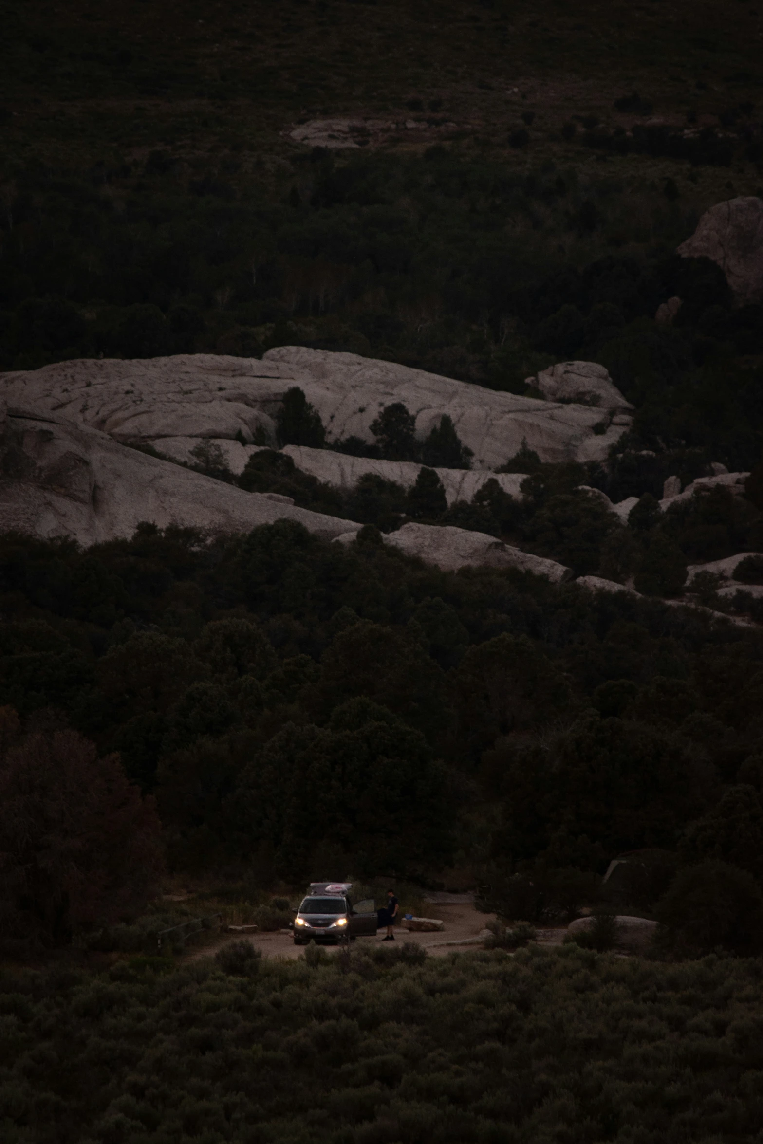 a vehicle is parked on a dirt road near the hills