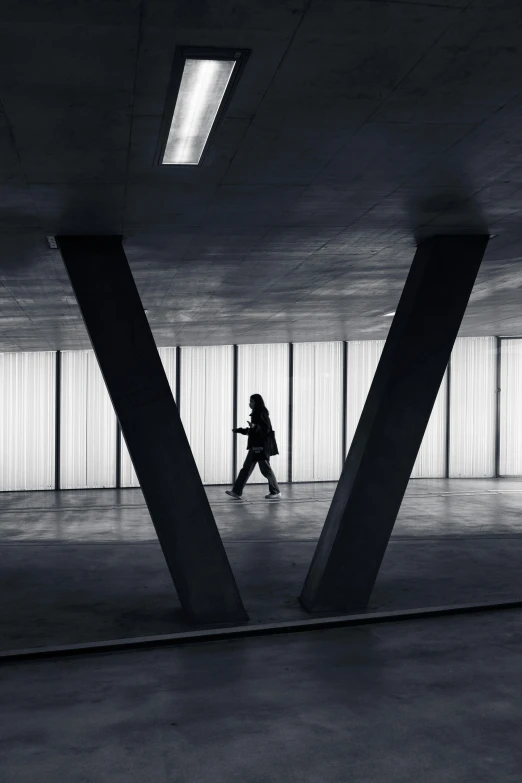 the woman is walking alone under a concrete structure