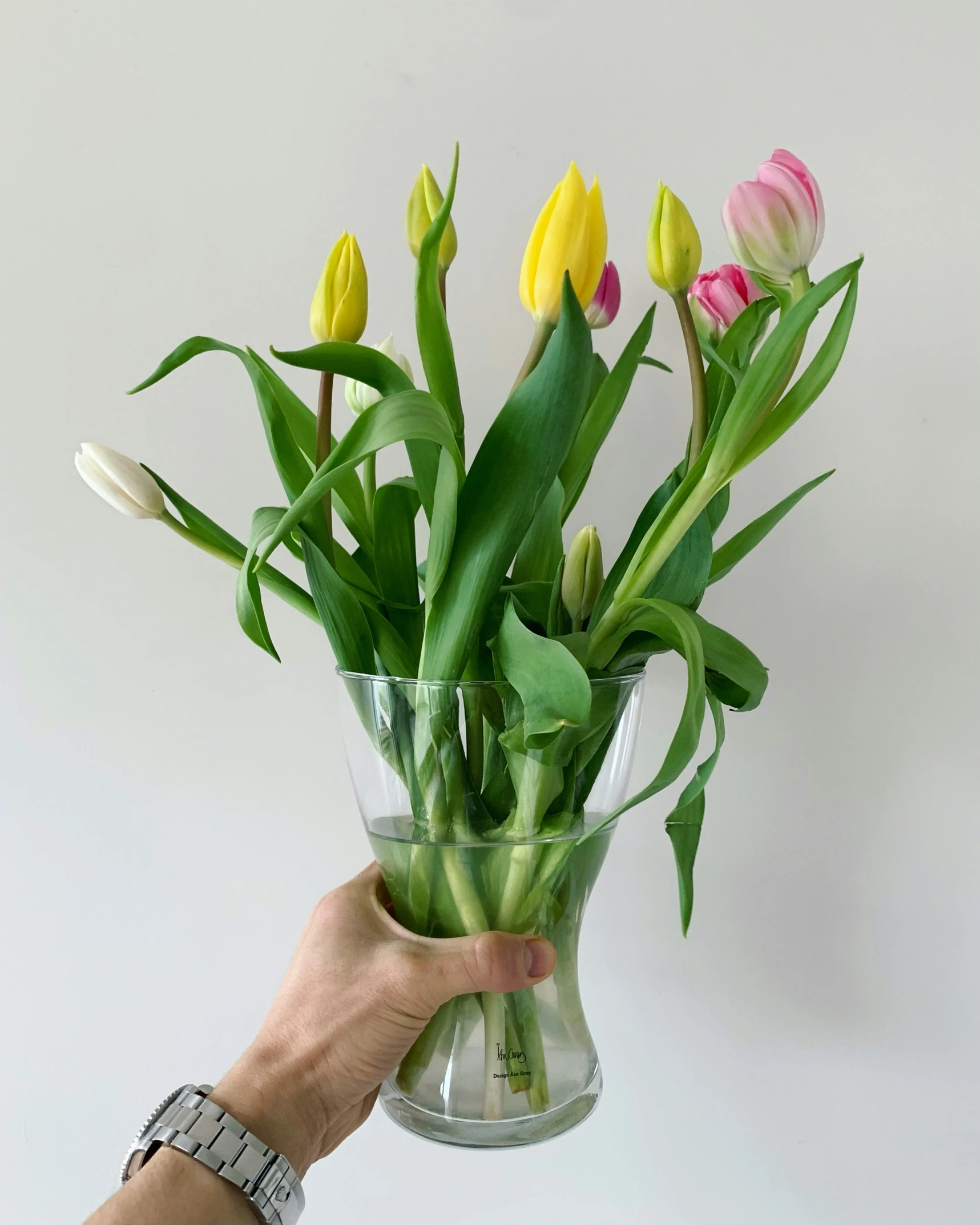a person is holding a vase with a bunch of flowers