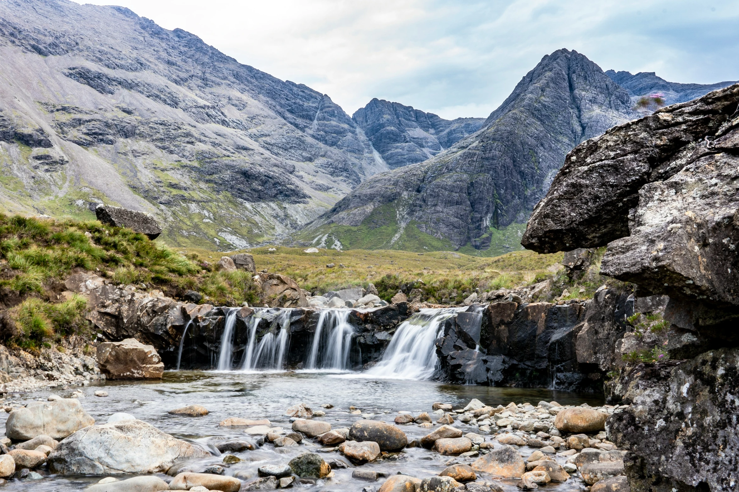 waterfall in middle of rocky valley on cloudy day