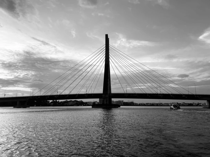 a bridge that is over water with clouds in the background