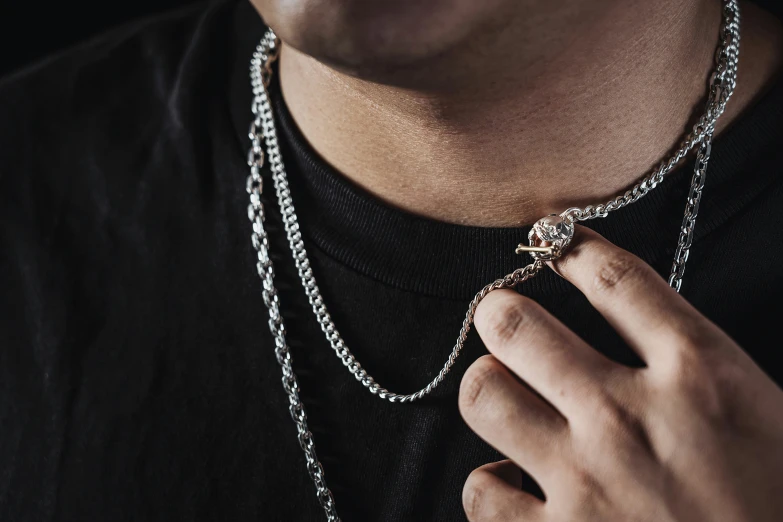 the man wears a necklace with an ornate cross on it