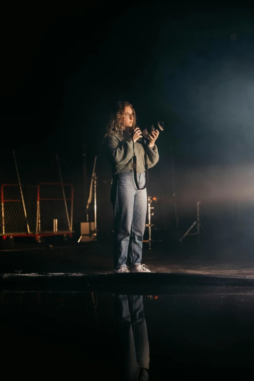 a girl stands alone with her camera looking back