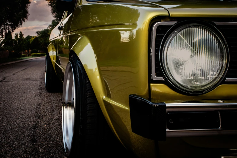 a yellow classic car sits on the street