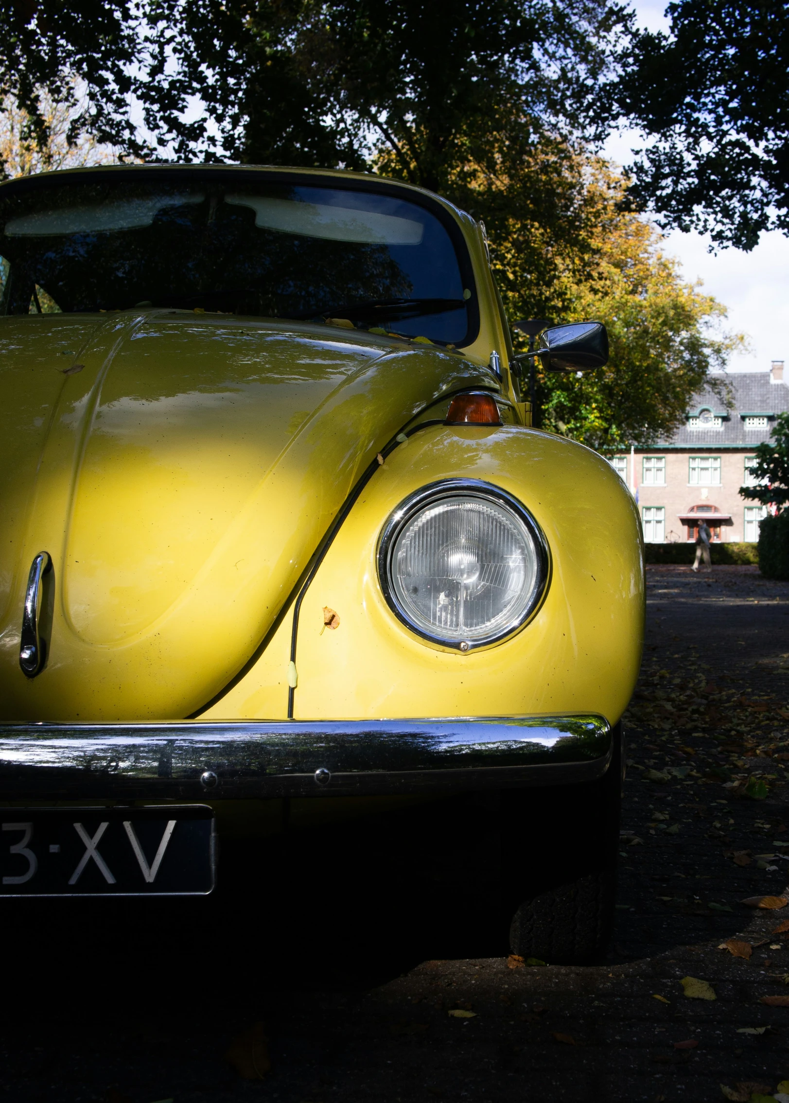 the front of an old yellow car in a driveway