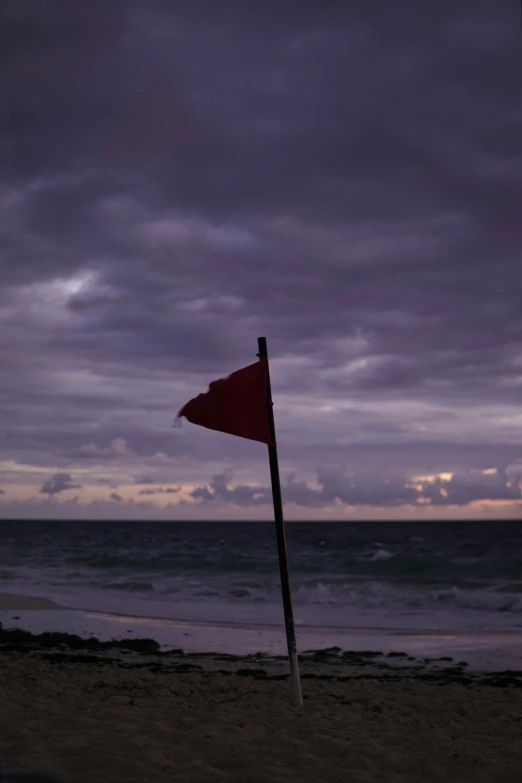 a flag with a red top standing in the sand