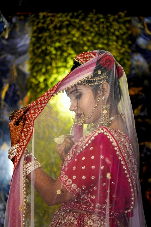 the bride poses for the camera, wearing her veil and red wedding dress