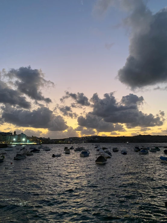 several small boats are seen in the water under cloudy skies