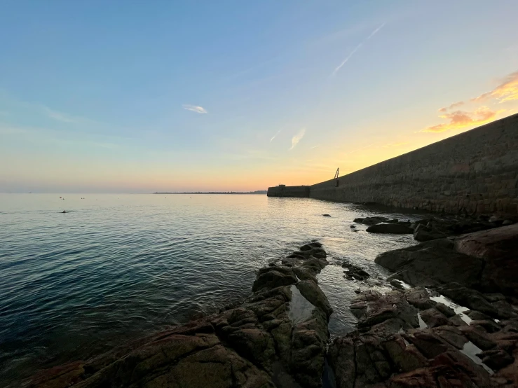 rocks are seen by the water at sunset