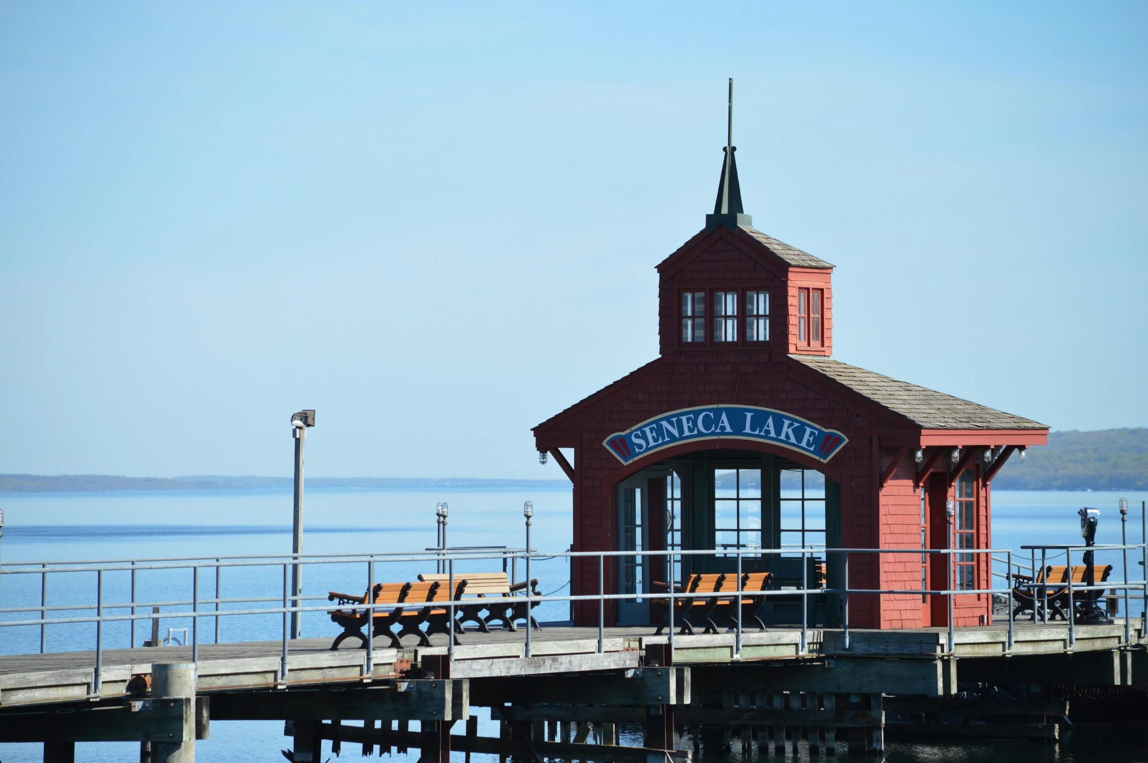 a clock tower at the end of a pier with benches