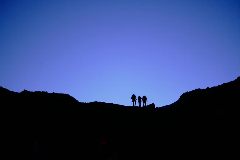 three people standing on a hill in the distance