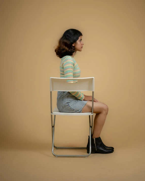 a woman sitting on top of a chair next to a tan wall