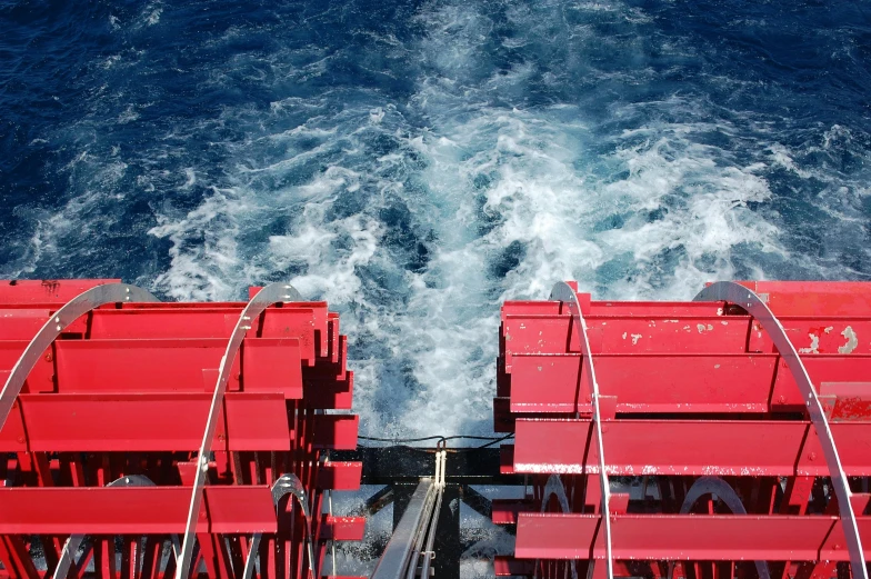 red chairs are waiting on a boat going through rough water