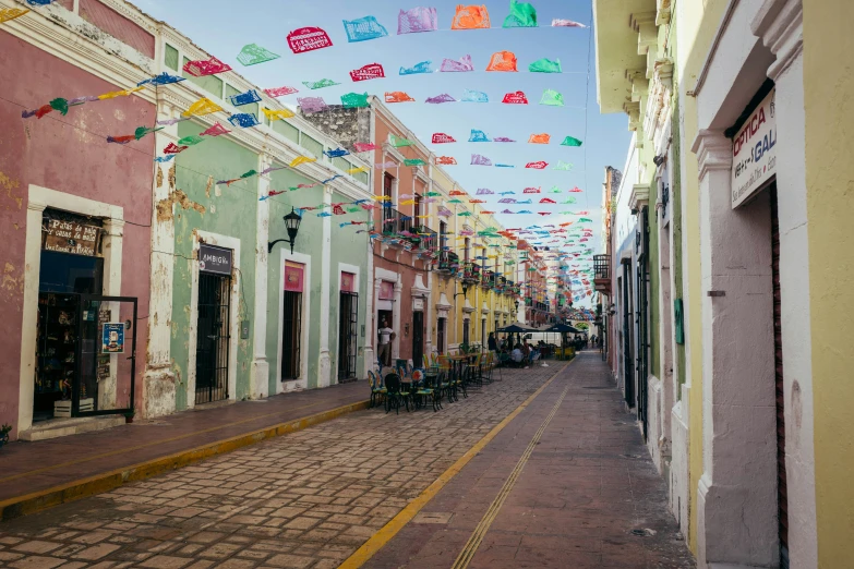 colorful flags are flying over a street lined with buildings