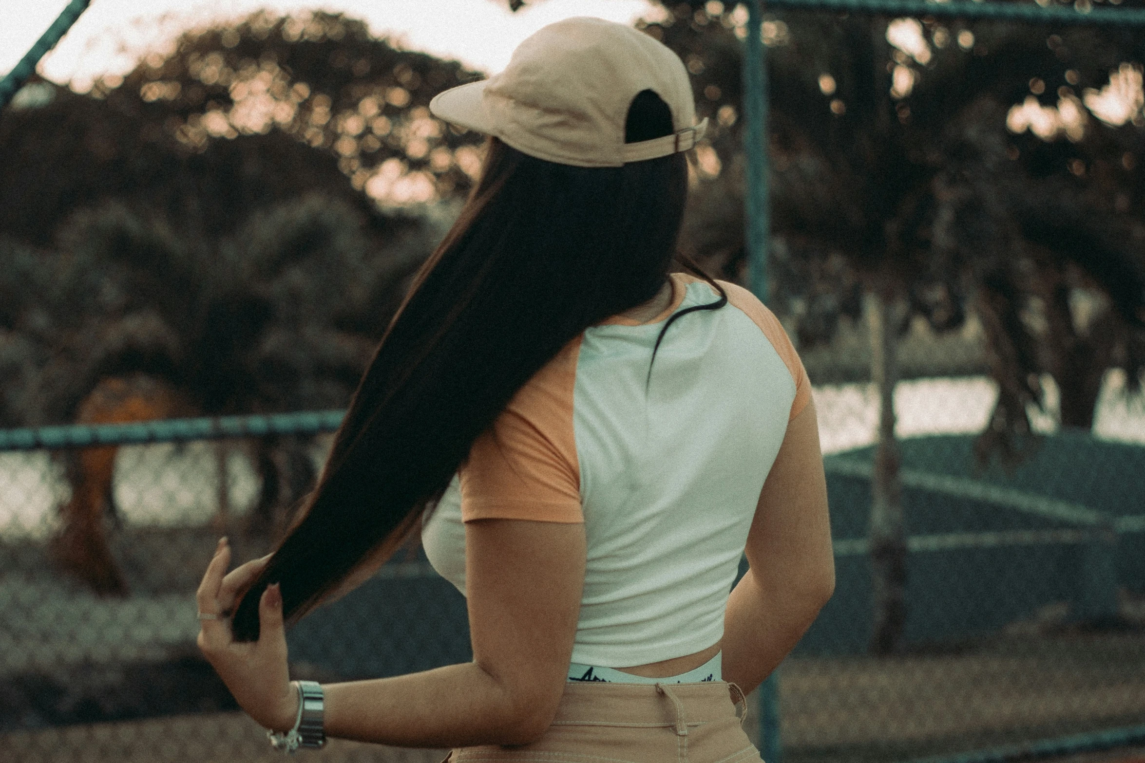 a girl with long hair and a baseball hat on