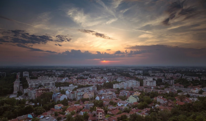 a city under a cloudy sky with sun peaking through