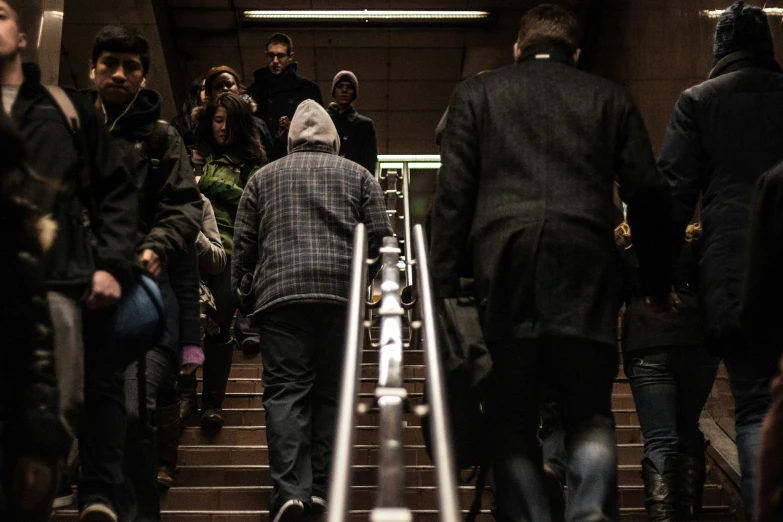 people are walking up an escalator in a subway