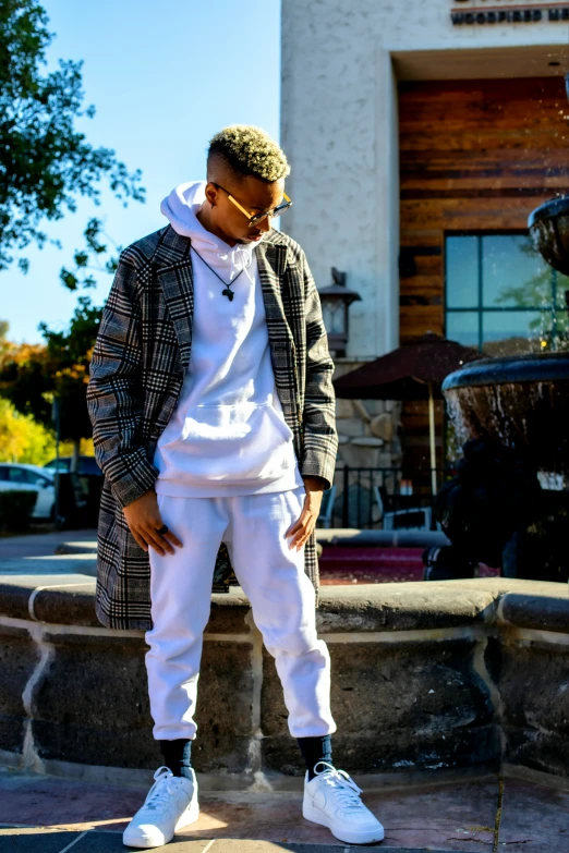 man in white sweat pants and plaid jacket standing by fountain