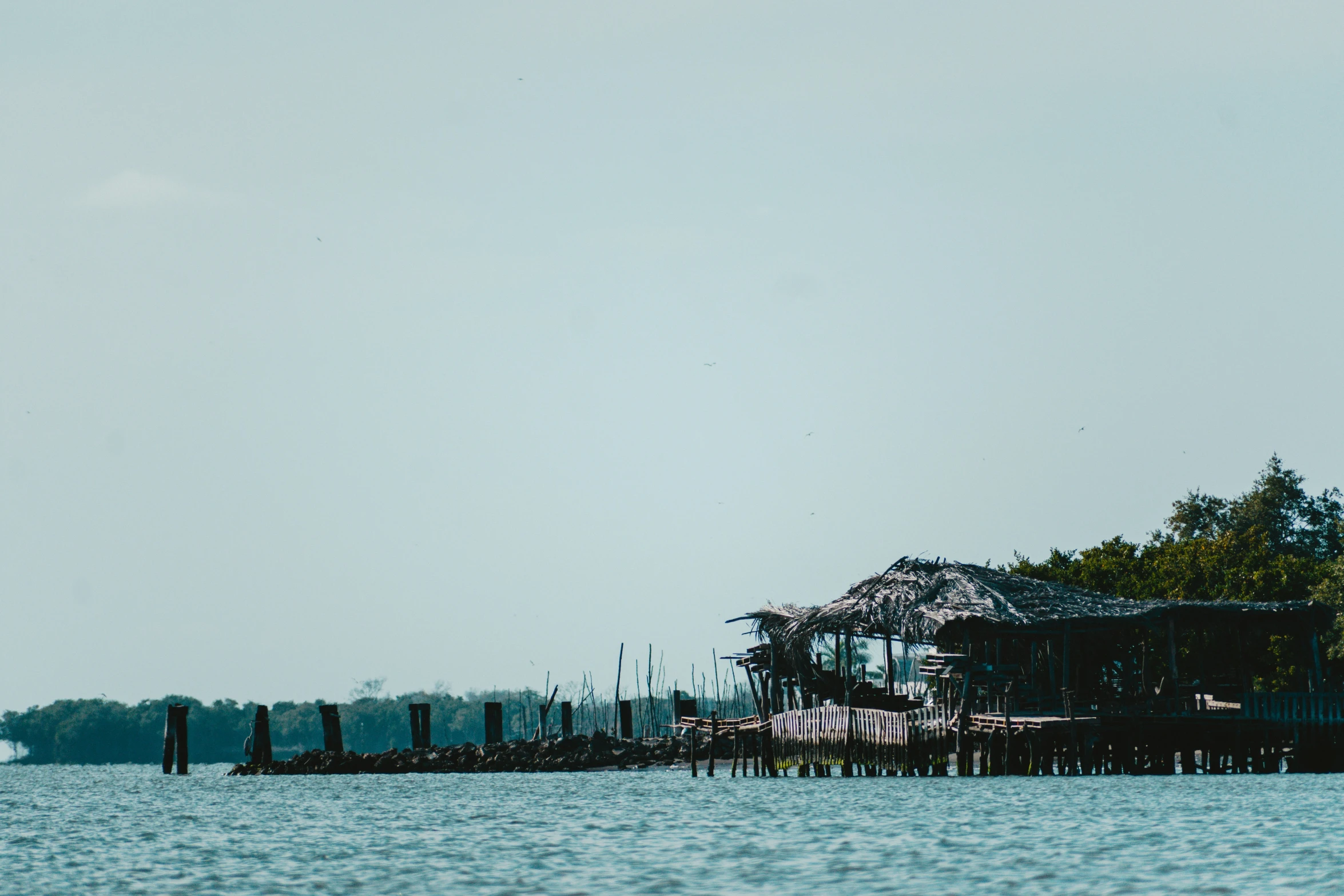 a pier sits in the middle of the ocean near some trees