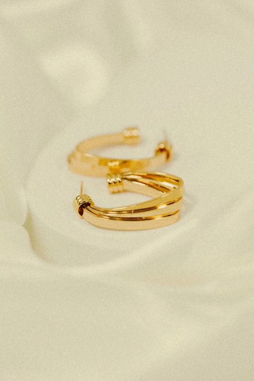 two gold rings sit on a white fabric