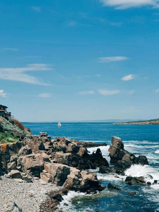 a view of some water with some rocks and a sailboat