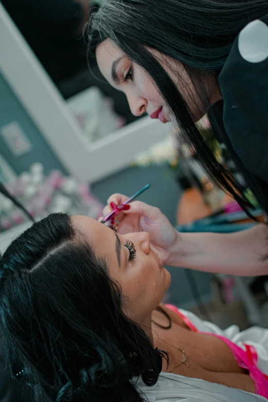 a woman getting her make - up done with an eyeliner