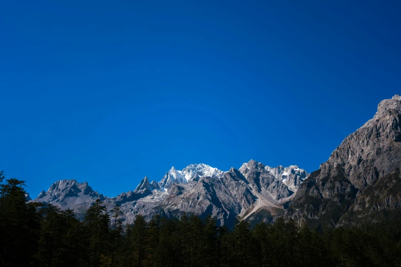 a large snowy mountain range with trees in the foreground